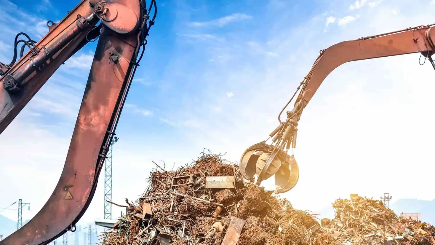 Industrial crane lifting scrap metal at a recycling yard under blue sky in Brisbane, Australia